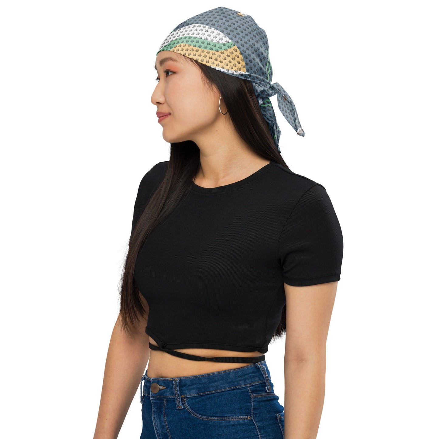 Woman wearing a blue, green, and cream patterned Nature & Soul Bandana tied at the back, paired with a black crop top and blue jeans, facing left in a casual style.