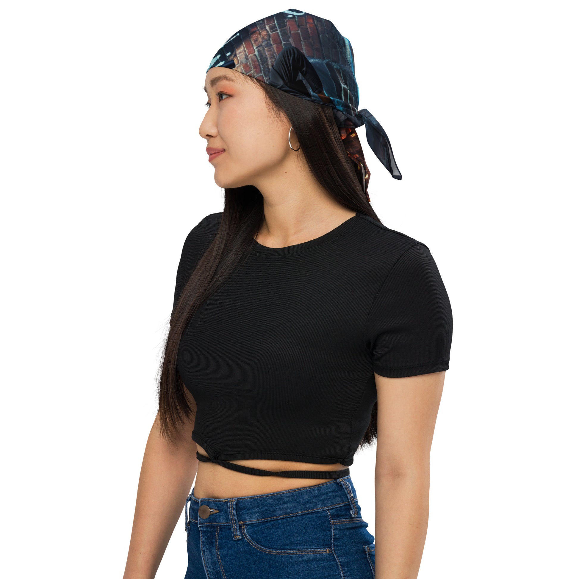 Woman wearing the Moonlit Mural Bandana tied at the back, showcasing a dark, artistic print, paired with a simple black top and blue jeans.