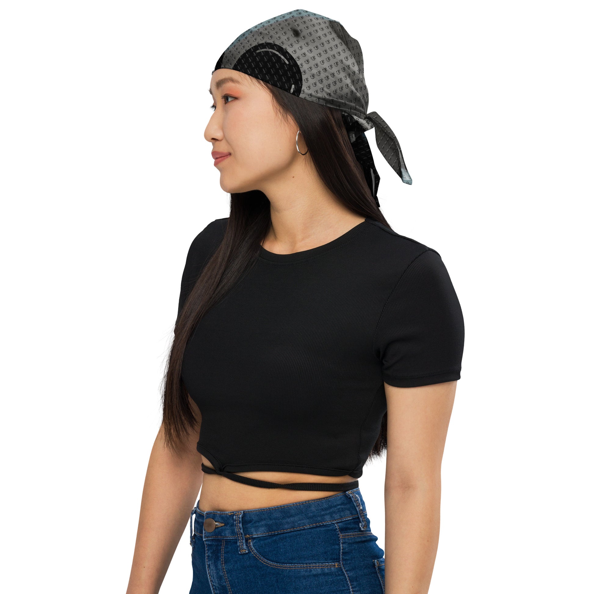 Woman wearing Abstract Art Bandana with dark and light gray abstract patterns tied at the back, paired with a black cropped top and blue jeans.