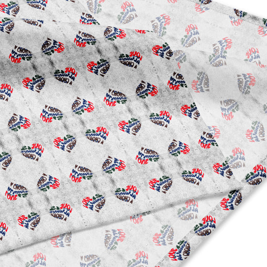 Close-up of a white all-over print fabric featuring small heart shapes with the phrase Love Is Always A Choice Bandana in red, blue, and black lettering arranged in a repeating pattern.