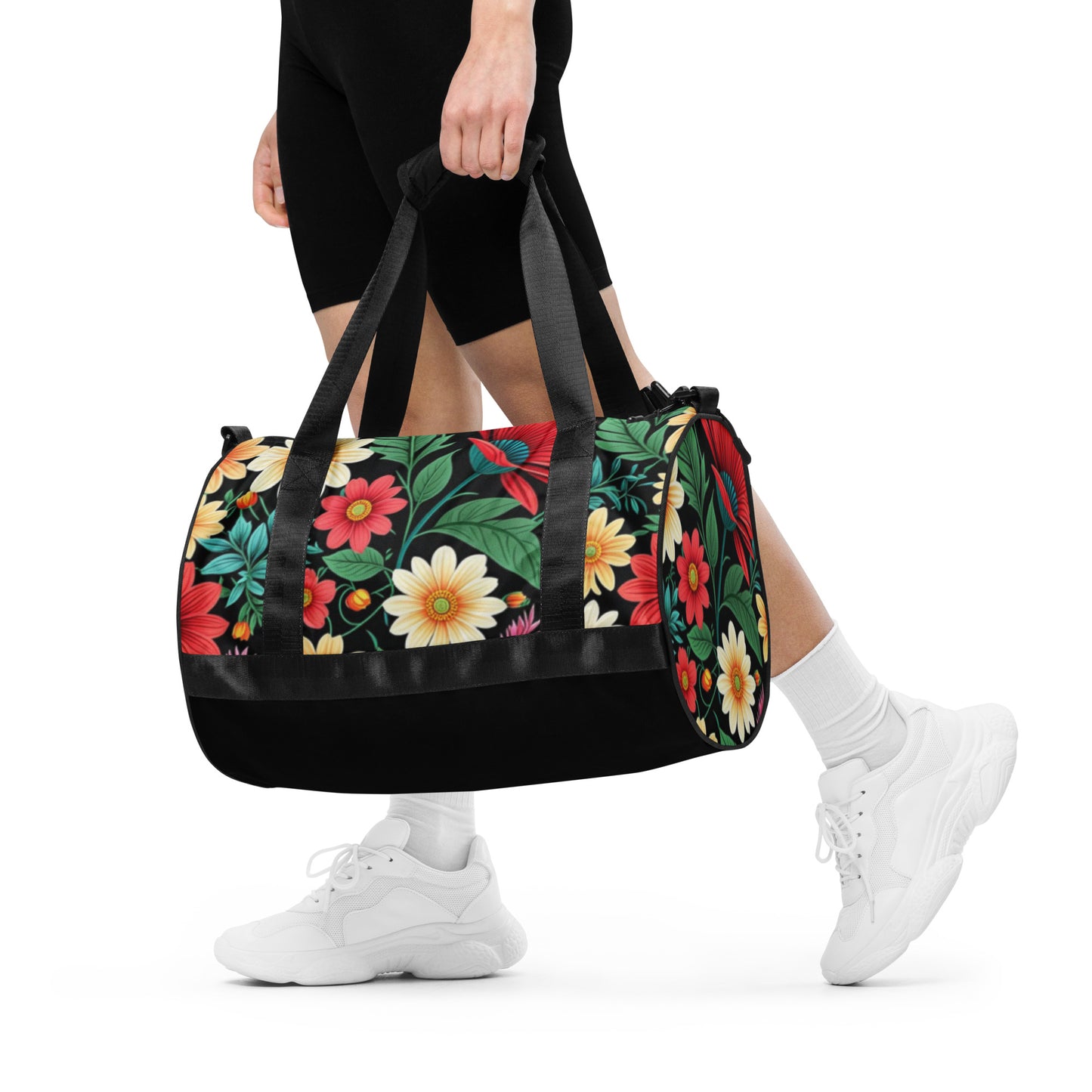 Person carrying a vibrant Gym Bag – Floral with colorful flower prints, black straps, and base, paired with white sneakers and black athletic shorts.