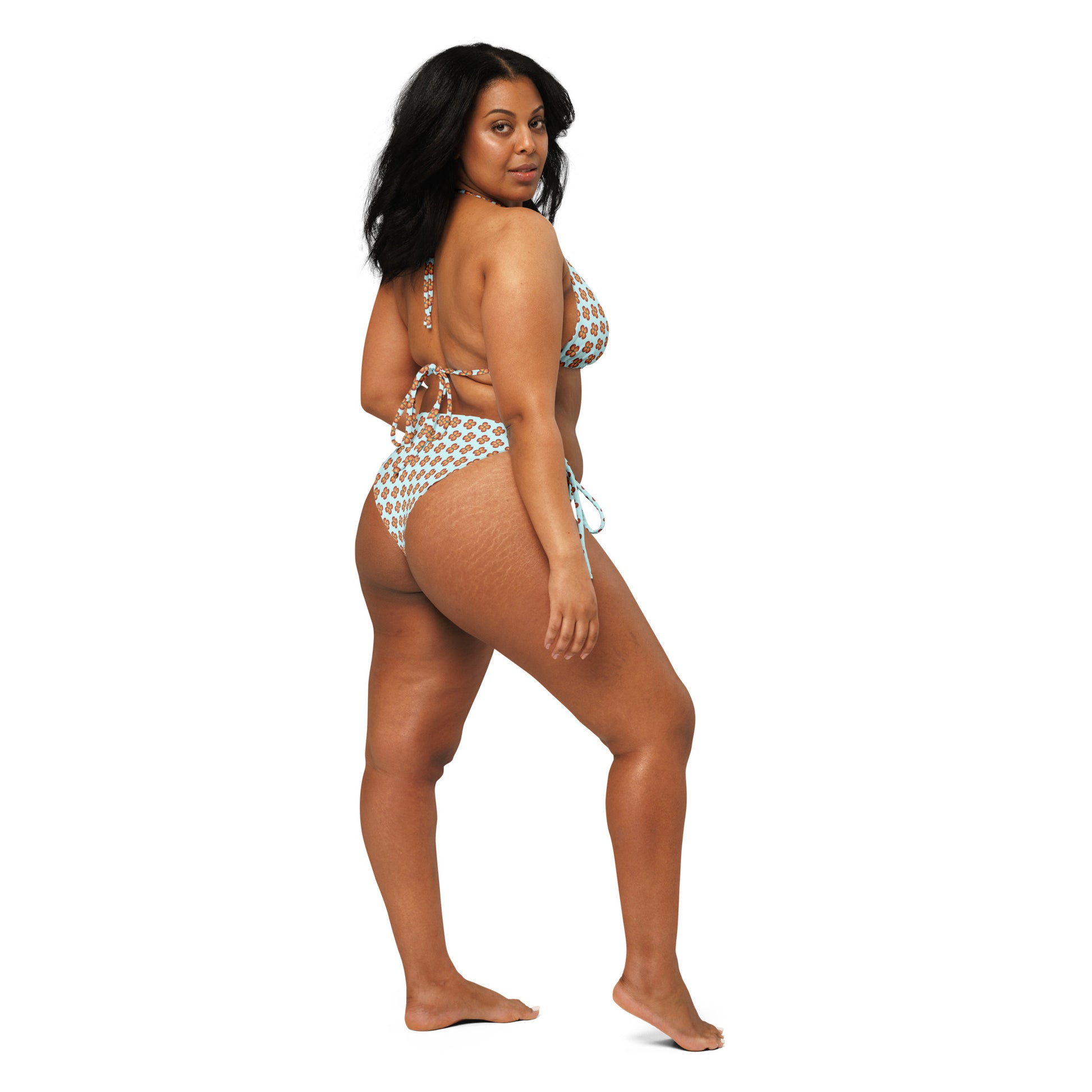 Woman modeling a Garden Teal Recycled String Bikini with a teal and white pattern, showcasing the back and side view of the eco-friendly swimwear.