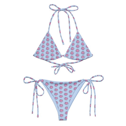 Blue Bloom Recycled String Bikini featuring a light blue fabric with a pink and white floral pattern, adjustable halter neck and side tie closures for a customizable fit.