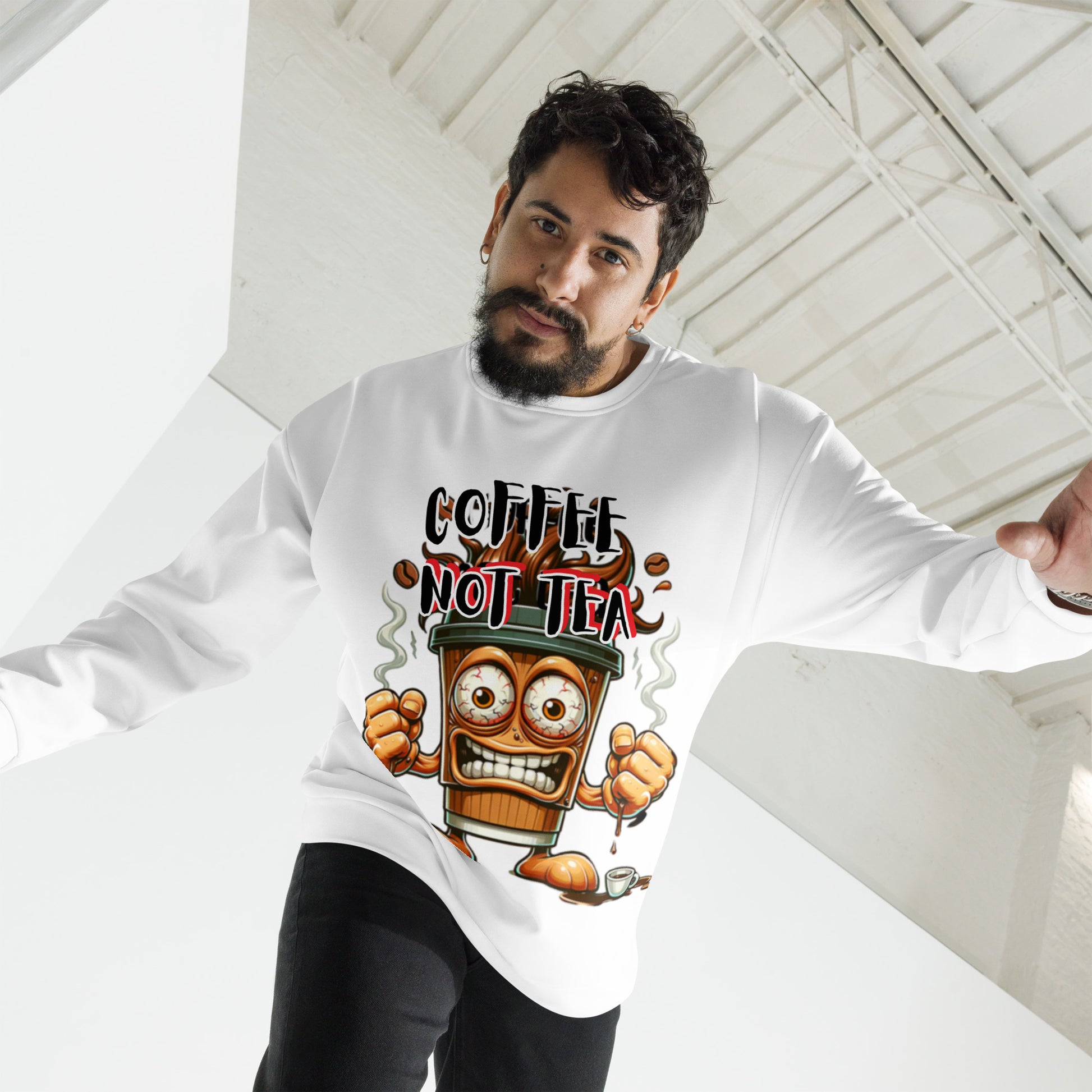 Man wearing a white Coffee Not Tea Sweatshirt featuring a bold graphic of an animated coffee cup with fists and steam, styled in a contemporary industrial space.