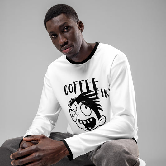 Man wearing a white Unisex Sweatshirt – Crazy Without Coffee with a black cartoon face and the words "Coffee First," sitting against a neutral gray background, showcasing faith-inspired apparel with purpose-driven messaging.