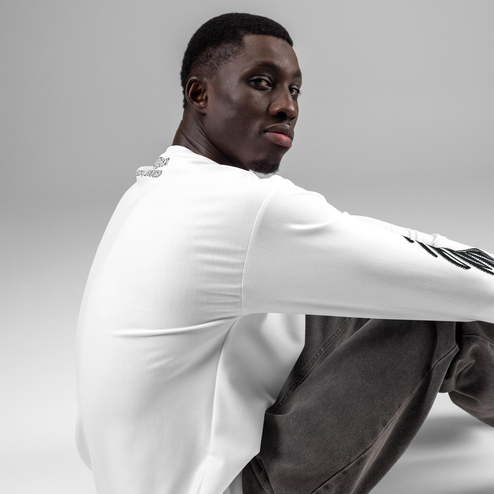 Man seated in white Unisex Sweatshirt – Afro Vibes with melanin-rich imagery and purpose-driven messaging, embodying faith-inspired apparel with a confident, inspirational look.