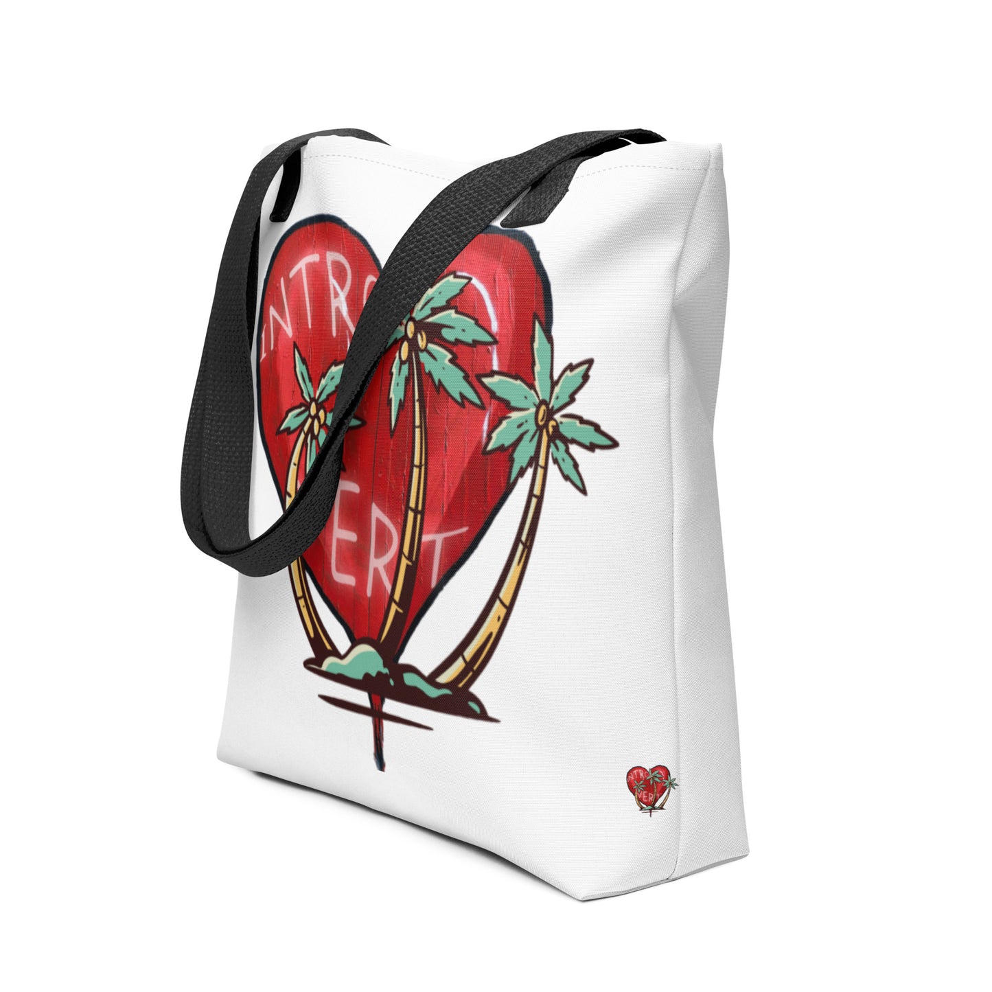 White tote bag with black straps featuring a large red broken heart design with palm trees and the word "Introvert," styled on the Tote Bag – Introvert.