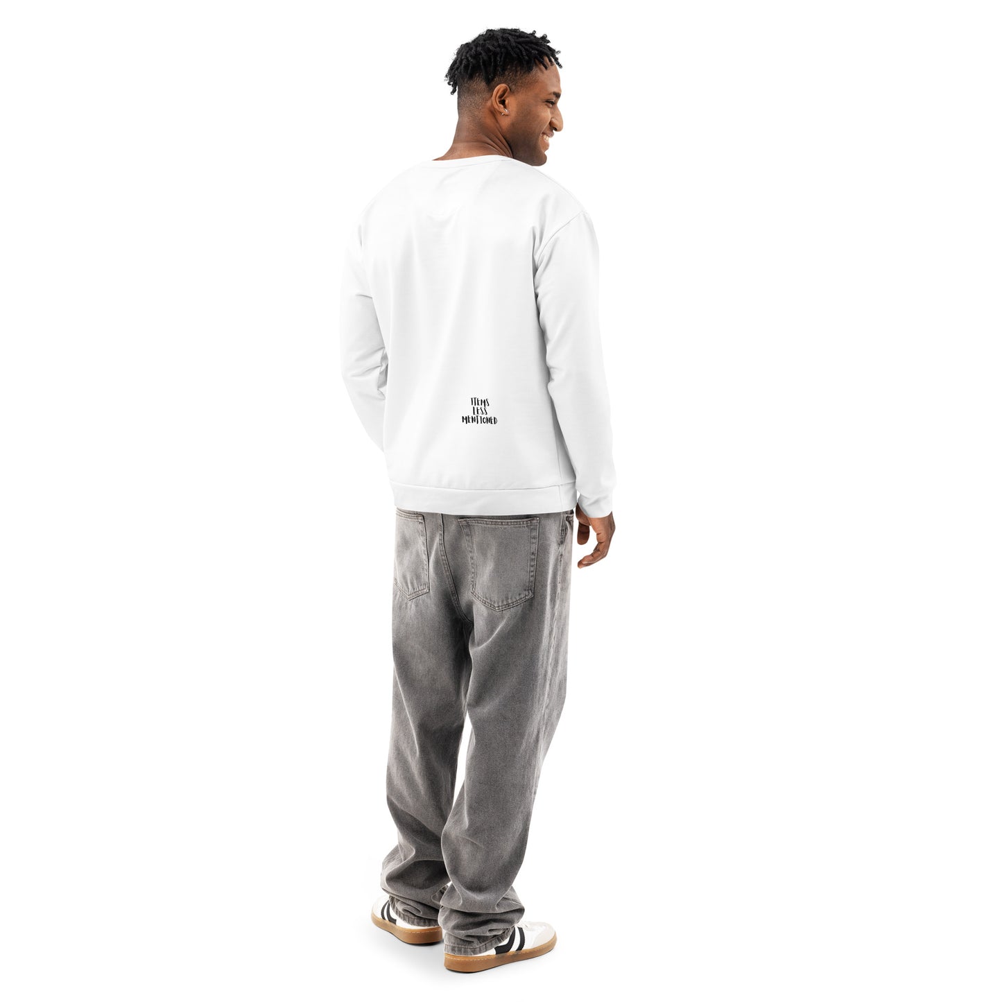 Man wearing a white Groovy Baby Sweatshirt with a small printed design on the lower back, paired with loose gray pants and casual sneakers, standing and looking to the side.