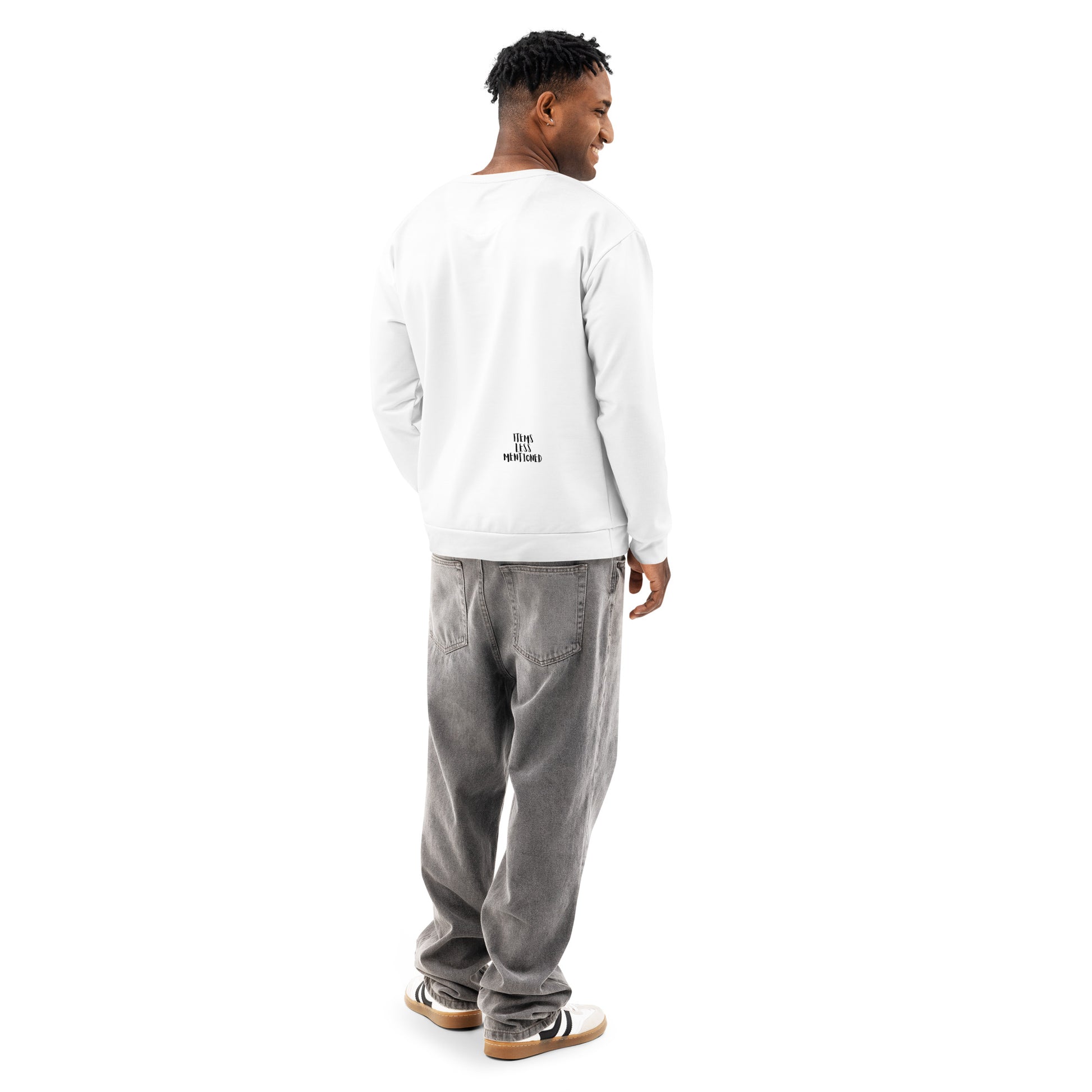Man wearing a white Groovy Baby Sweatshirt with a small printed design on the lower back, paired with loose gray pants and casual sneakers, standing and looking to the side.