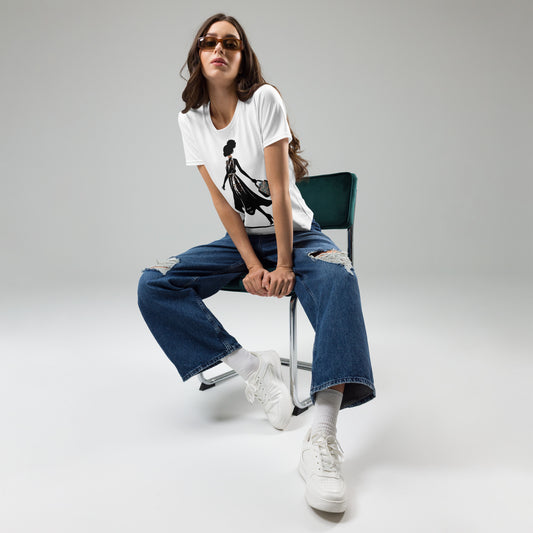 Woman wearing a white Afro Puff Strut Women's T-Shirt with black graphic design, paired with ripped blue jeans, white sneakers, and sunglasses, sitting on a chair.