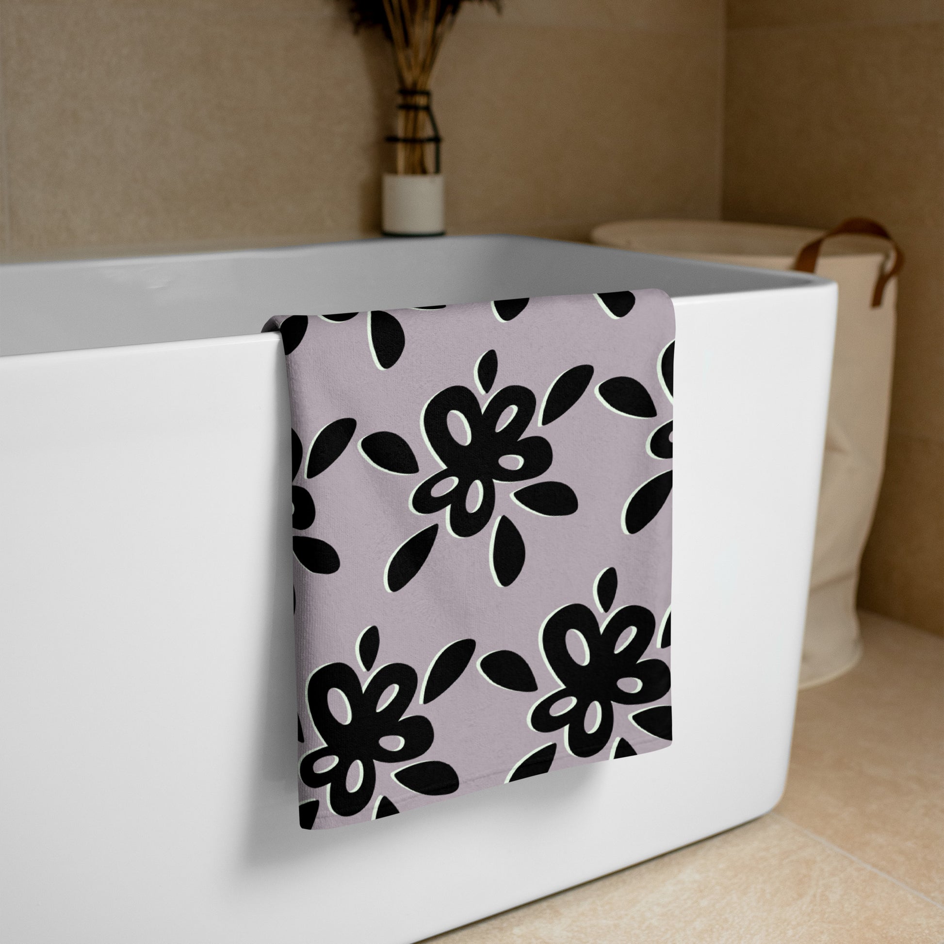 Hand Towel – Floral with bold black flower patterns on a soft lavender background hanging over a white bathtub in a cozy bathroom setting.