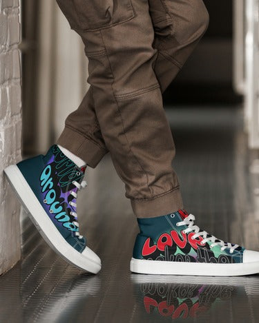 Person wearing Men's High Top Sneakers – Graffiti with colorful graffiti-inspired design, white laces, and white soles, paired with brown pants, standing indoors on a reflective surface.