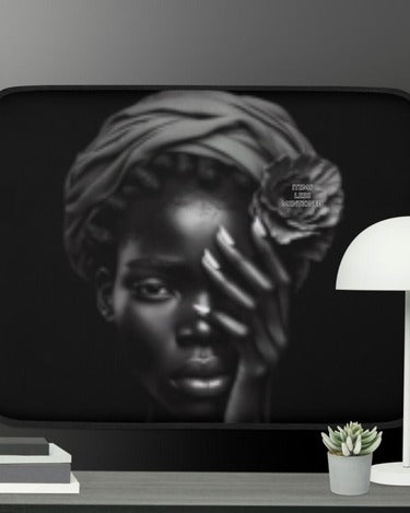 Head Wrap Queen Laptop Sleeve featuring a monochrome artistic portrait of a Black woman with a head wrap and hand partially covering her face, displayed on a modern desk near a lamp and succulent plant.
