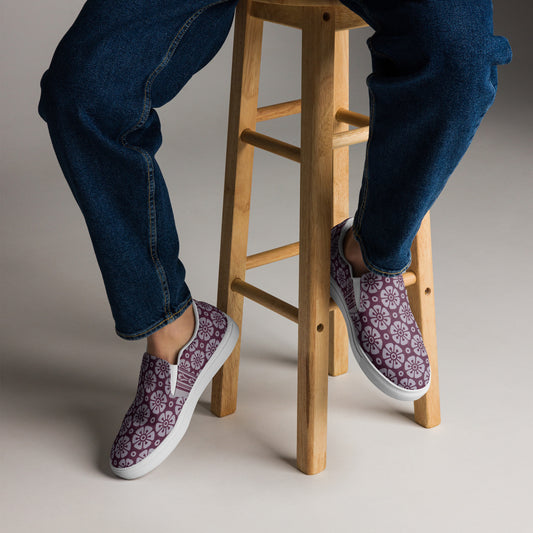 Person wearing Women's High Top Sneakers – Floral in Cranberry with floral patterns, paired with dark blue jeans, sitting on a wooden stool showcasing faith-inspired apparel and purpose-driven style.