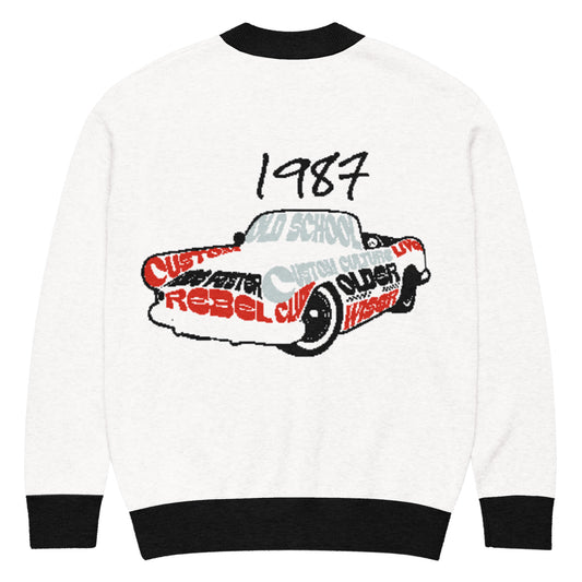 Back view of a white Knitted Cardigan – 1987 Rebel featuring a retro car illustration with words like rebel and custom in black and red, blending faith-inspired style and purpose-driven messaging.