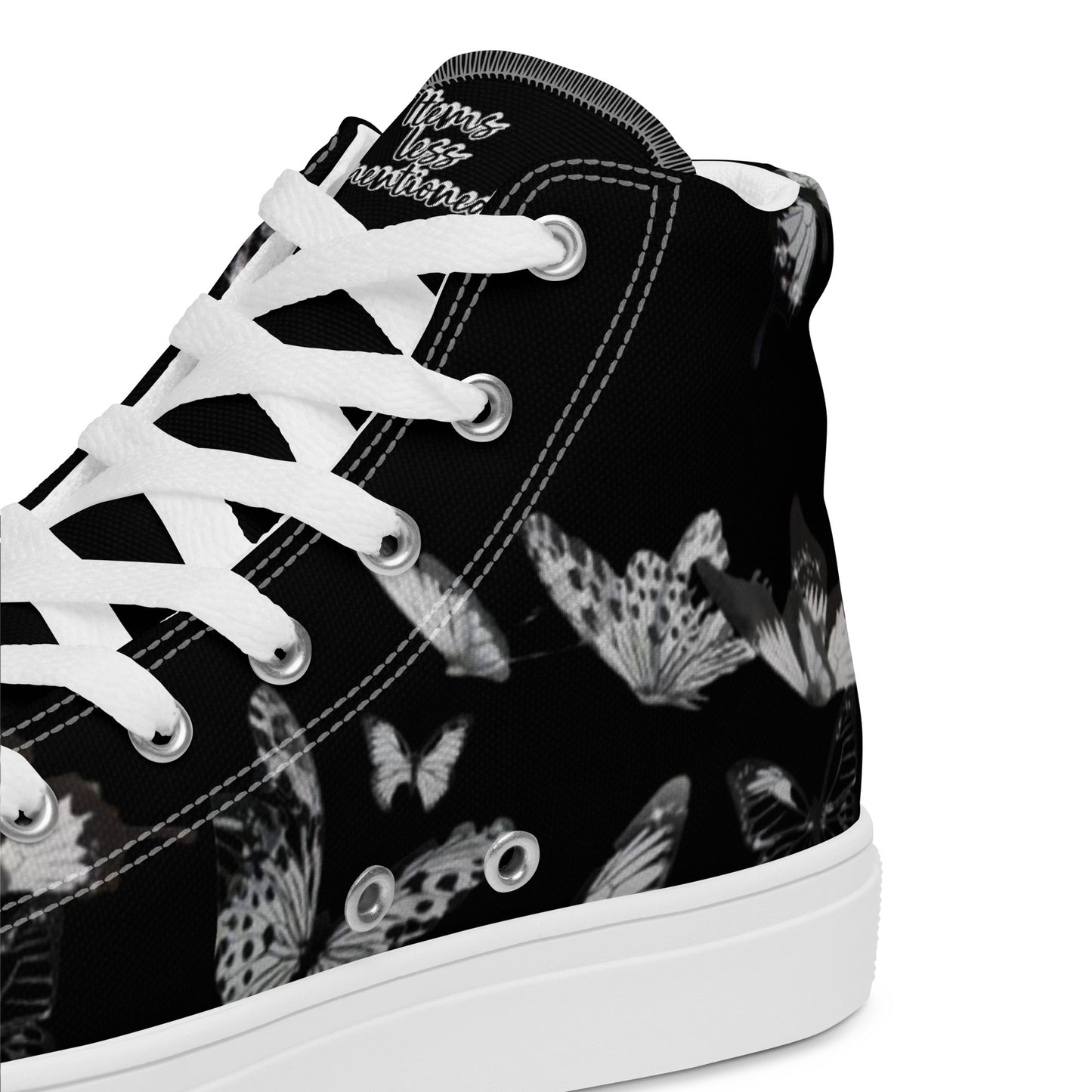 Close-up of a black canvas Women's High Top Sneakers – Butterfly with white laces and a white sole, featuring a subtle butterfly pattern and faith-inspired messaging on the tongue.
