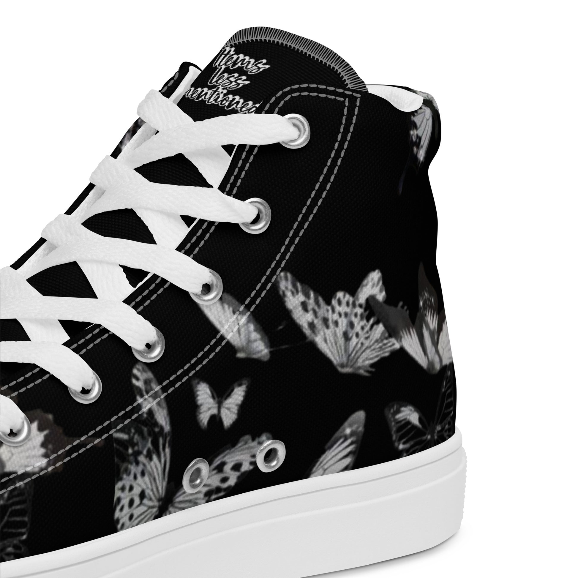 Close-up of a black canvas Women's High Top Sneakers – Butterfly with white laces and a white sole, featuring a subtle butterfly pattern and faith-inspired messaging on the tongue.