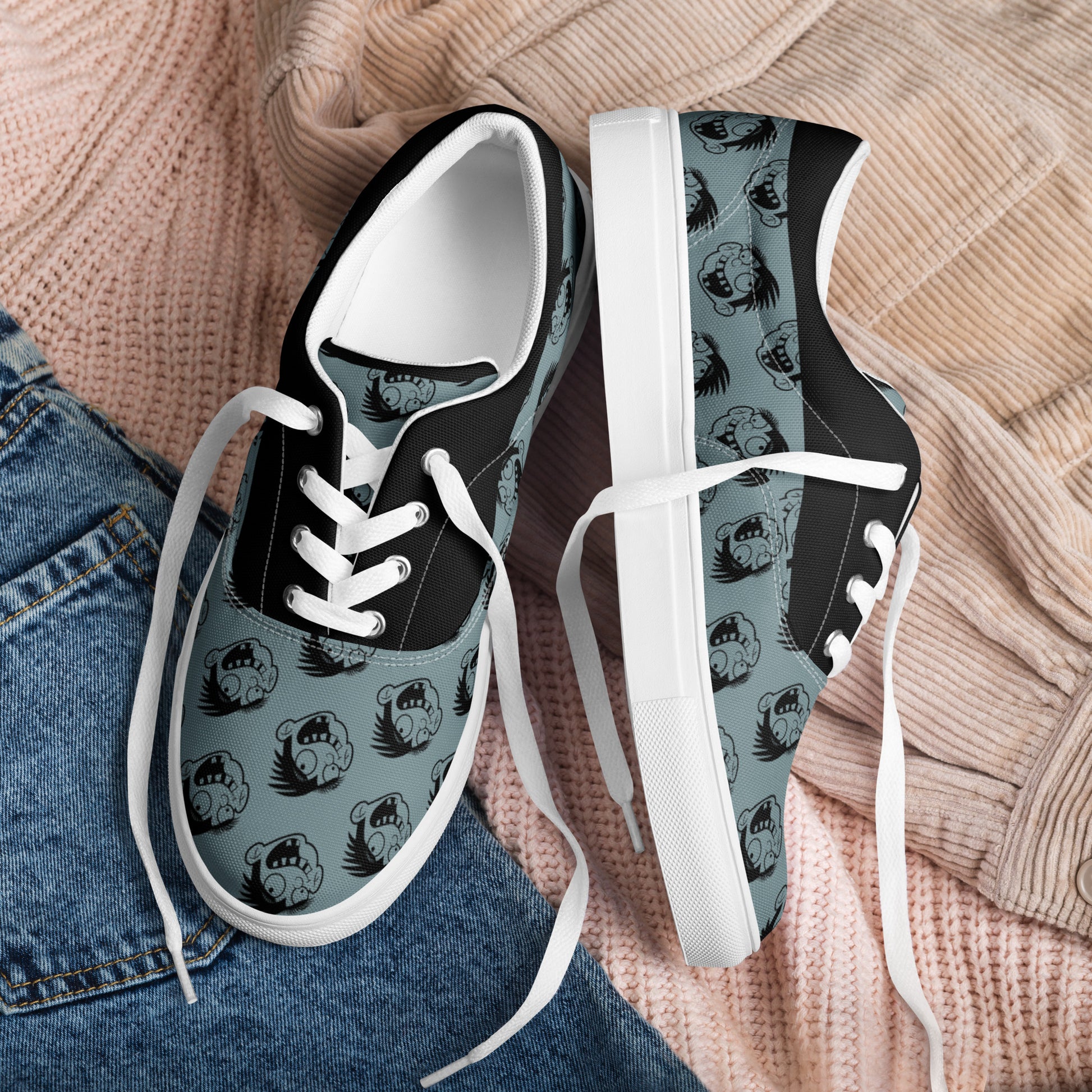 Pair of Cartoon Face Women's Lace-Up Canvas Shoes in black and gray with a repeated cartoon face pattern, styled casually with denim and knitwear background.